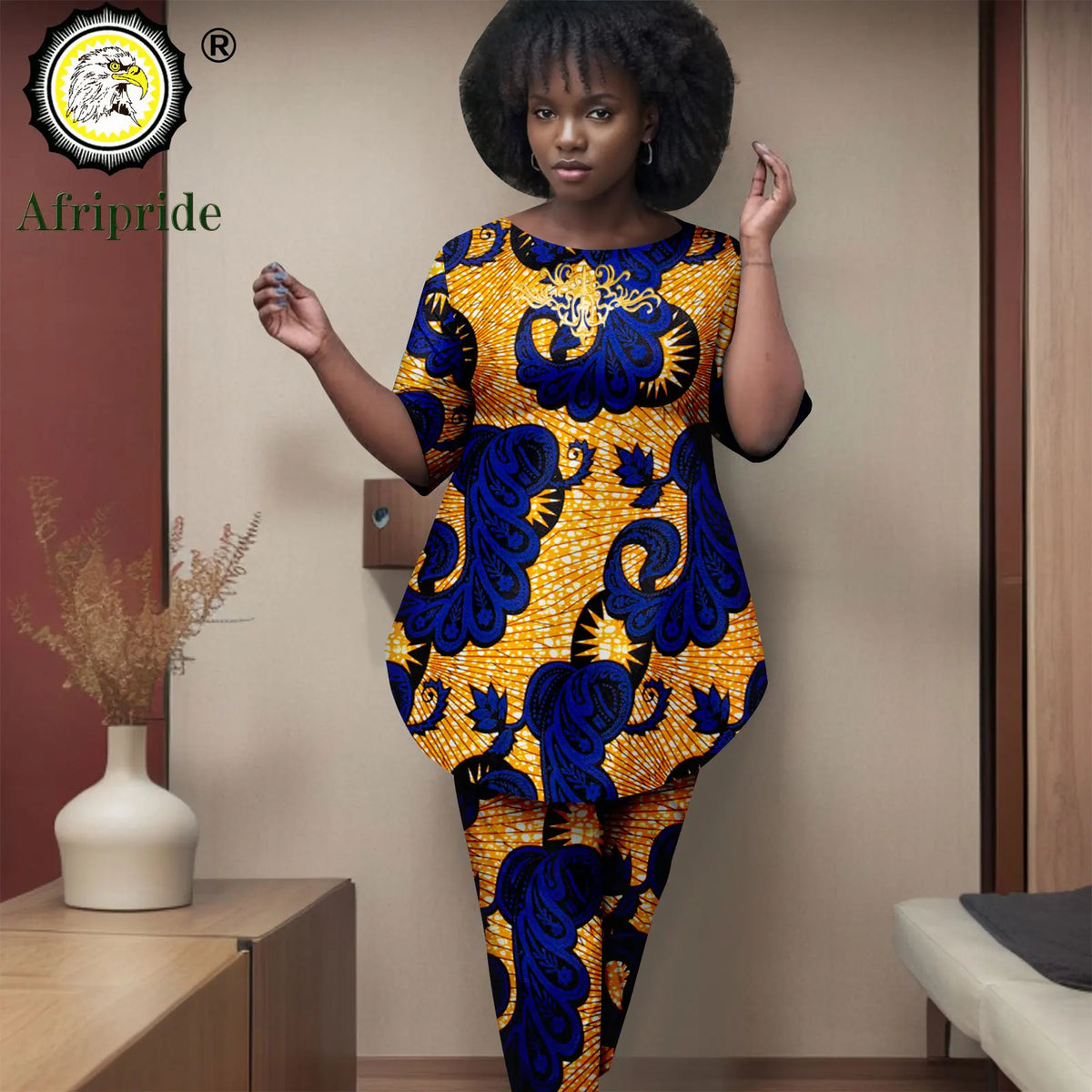 Woman wearing a blue and yellow patterned dress in an indoor setting with 'Afripride' branding.